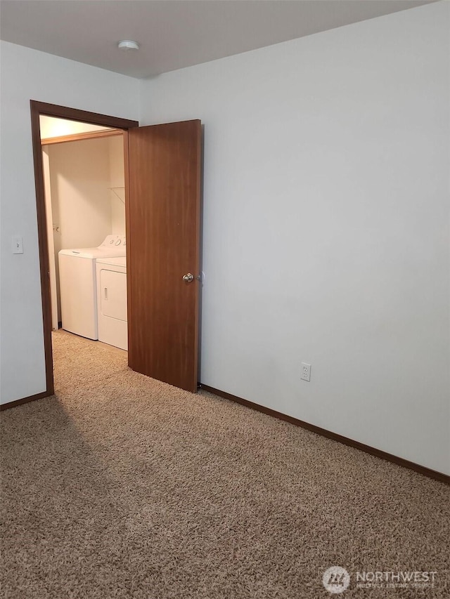 carpeted empty room featuring washing machine and clothes dryer