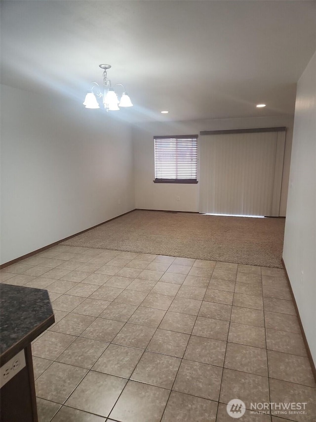 tiled spare room featuring a notable chandelier