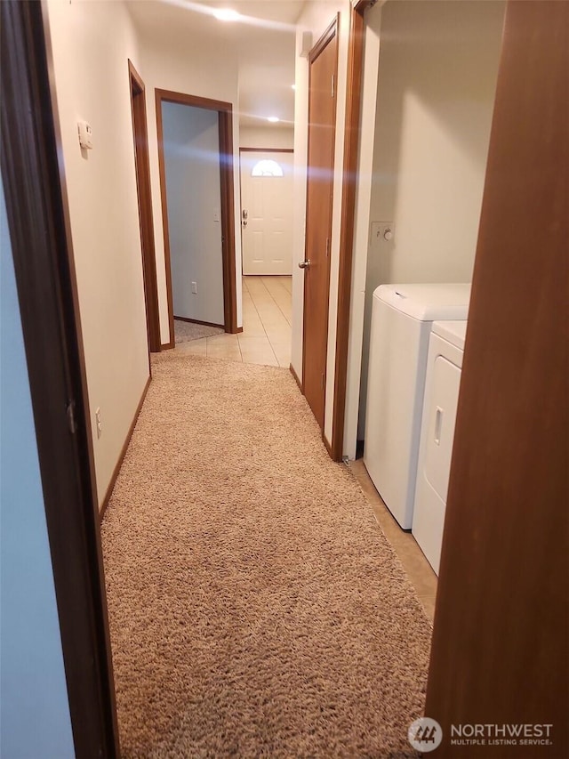 corridor with washing machine and dryer and light tile patterned floors