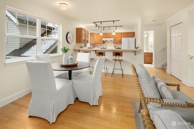 dining space featuring ornamental molding, rail lighting, and light wood-type flooring