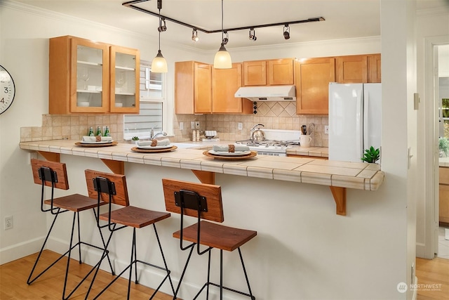 kitchen featuring stove, tile countertops, a breakfast bar, and white fridge