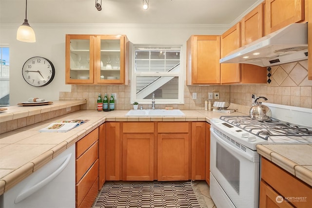 kitchen with sink, gas range gas stove, tile counters, ornamental molding, and stainless steel dishwasher