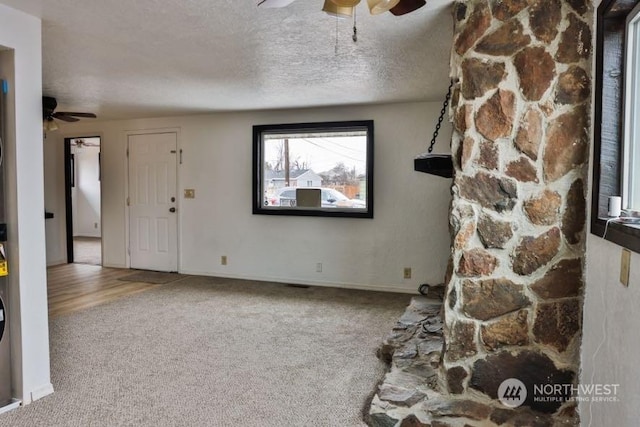 unfurnished living room featuring ceiling fan, carpet floors, and a textured ceiling