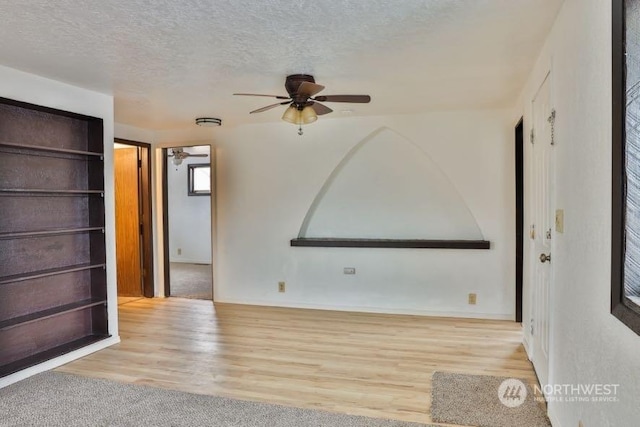 spare room with ceiling fan, light hardwood / wood-style floors, and a textured ceiling