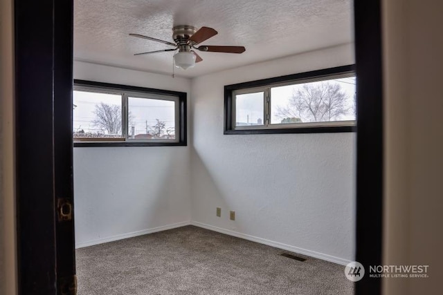 carpeted empty room with ceiling fan and a textured ceiling