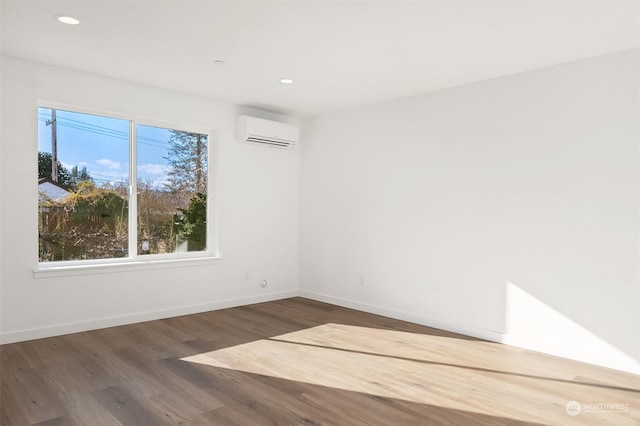 spare room featuring dark hardwood / wood-style flooring and a wall unit AC