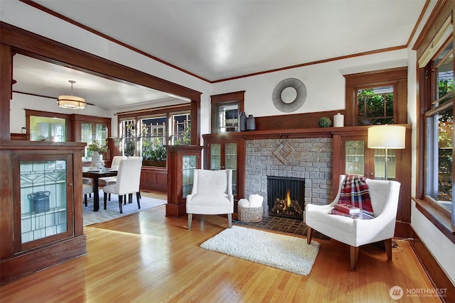 living area featuring light wood-style floors, a brick fireplace, and ornamental molding