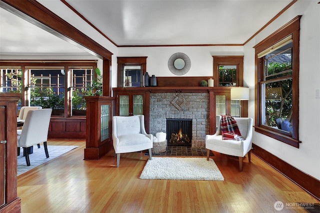 sitting room with a brick fireplace, light wood-style flooring, and a wealth of natural light