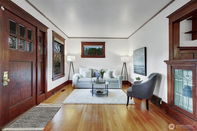 interior space featuring ornamental molding, light wood-style flooring, and baseboards