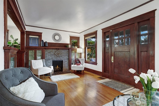 interior space featuring wood finished floors, visible vents, baseboards, ornamental molding, and a brick fireplace