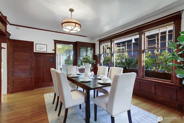 dining space with light wood-style floors and a wainscoted wall