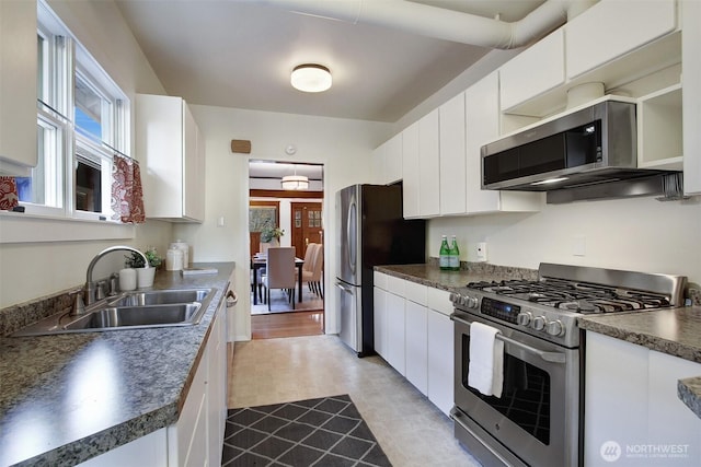 kitchen featuring dark countertops, white cabinetry, appliances with stainless steel finishes, and a sink