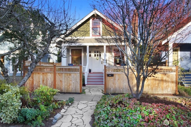 view of front of property with a fenced front yard and a porch