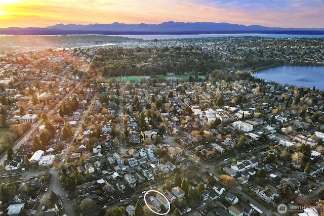 aerial view at dusk featuring a residential view and a water and mountain view