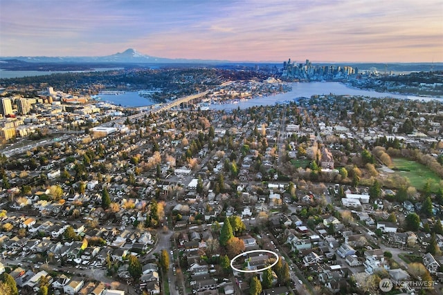 aerial view at dusk with a view of city and a water and mountain view