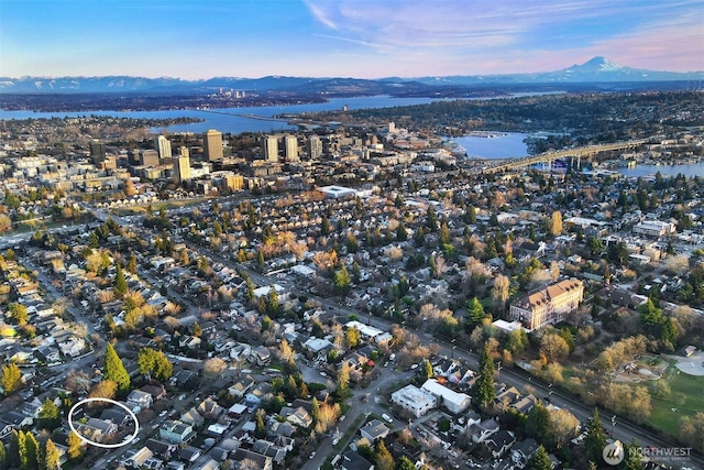 aerial view at dusk featuring a city view and a water and mountain view