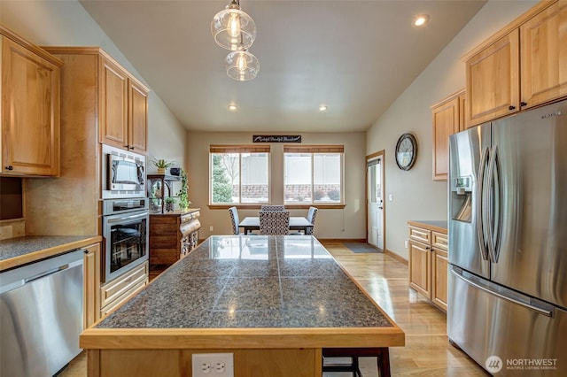 kitchen with light hardwood / wood-style flooring, a breakfast bar, a center island, decorative light fixtures, and stainless steel appliances