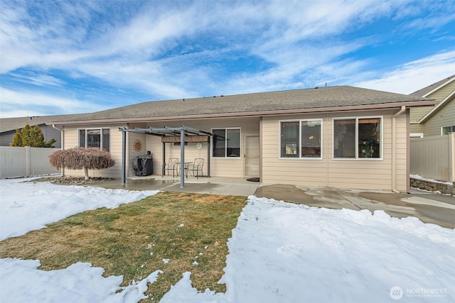 snow covered back of property with a yard, a patio, and a pergola