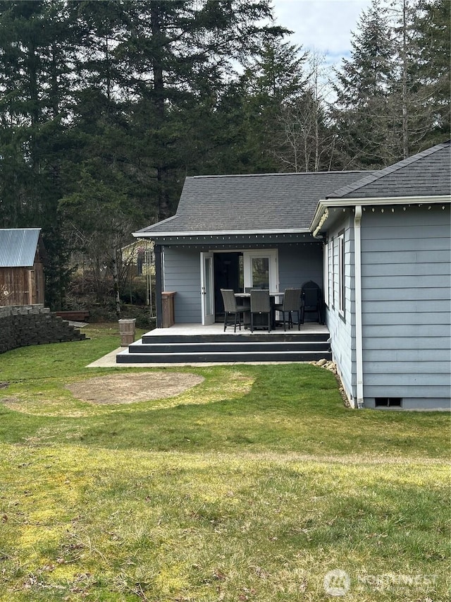 rear view of property with roof with shingles, outdoor dining area, a lawn, and a wooden deck