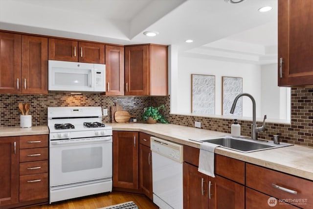 kitchen with tasteful backsplash, sink, white appliances, and a raised ceiling