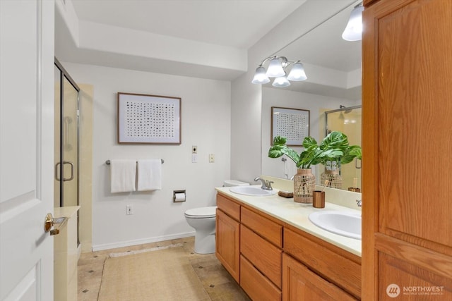 bathroom featuring a shower with door, vanity, and toilet