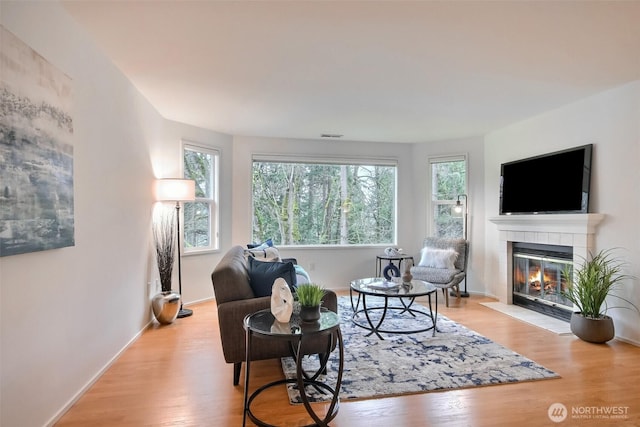 living room featuring a tile fireplace and light hardwood / wood-style floors