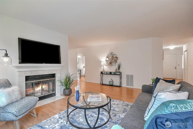 living room featuring a tiled fireplace and light hardwood / wood-style flooring