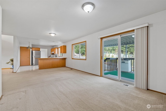 unfurnished living room featuring a healthy amount of sunlight and light carpet