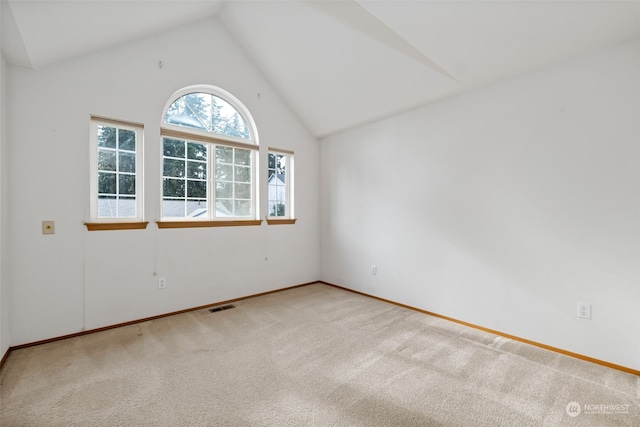 carpeted empty room with high vaulted ceiling