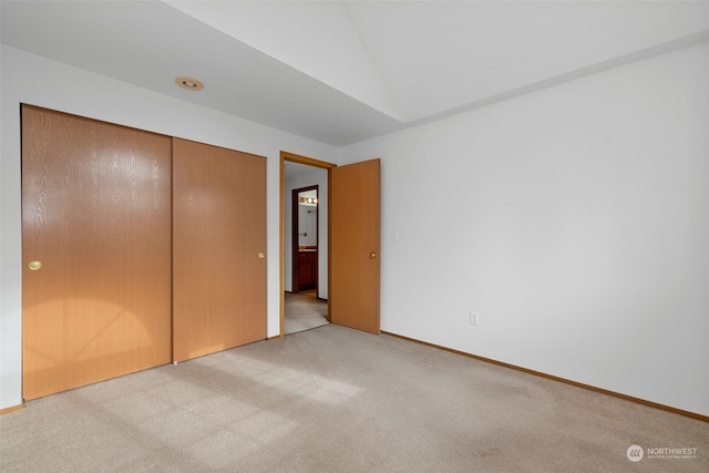 unfurnished bedroom featuring lofted ceiling, light colored carpet, and a closet