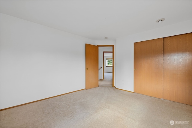 unfurnished bedroom featuring light carpet and a closet