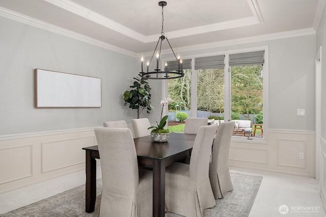 dining space featuring a raised ceiling, light carpet, a decorative wall, and a notable chandelier