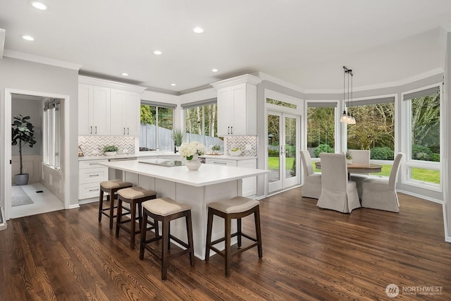 kitchen with light countertops, a center island, decorative light fixtures, and white cabinets