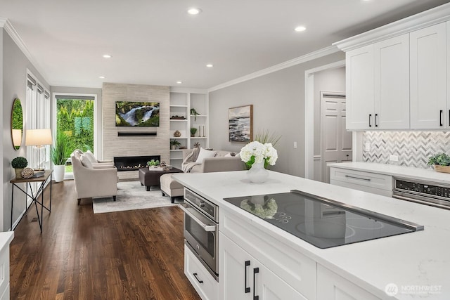 kitchen with dark wood finished floors, ornamental molding, open floor plan, black electric cooktop, and white cabinetry