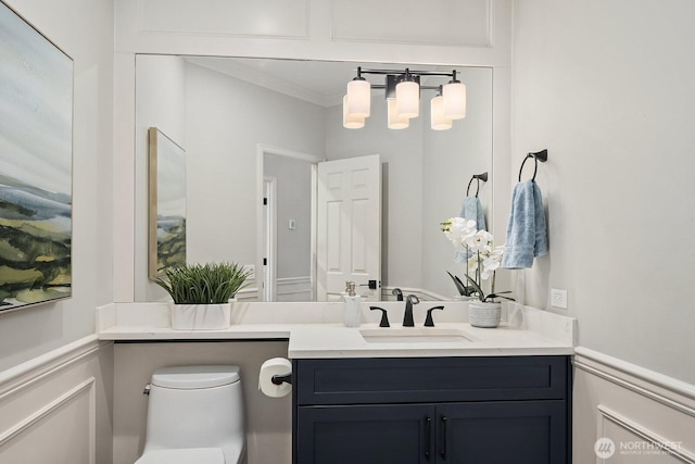 half bathroom with a decorative wall, crown molding, vanity, and toilet