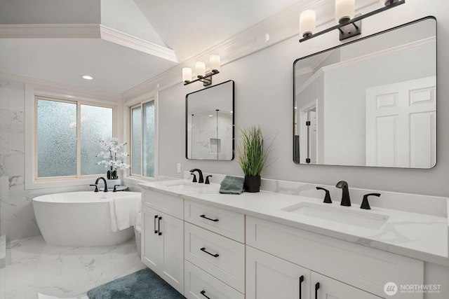 full bathroom featuring double vanity, marble finish floor, a freestanding tub, and a sink