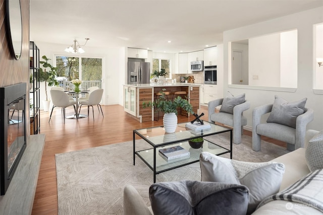 living room featuring a notable chandelier, a premium fireplace, and light wood-type flooring