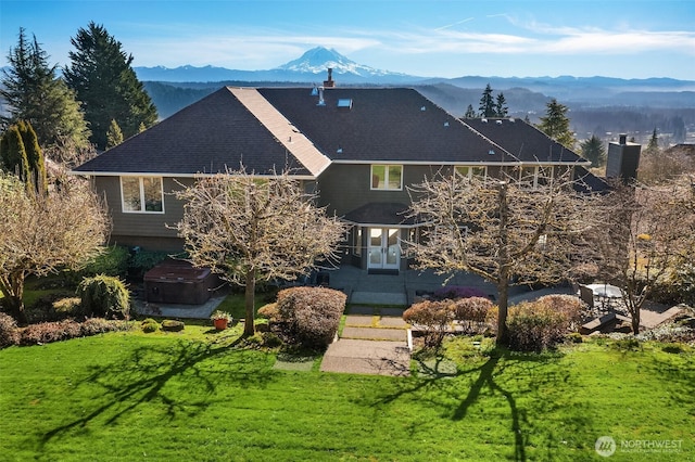 view of front of house with a front yard, a mountain view, and a hot tub