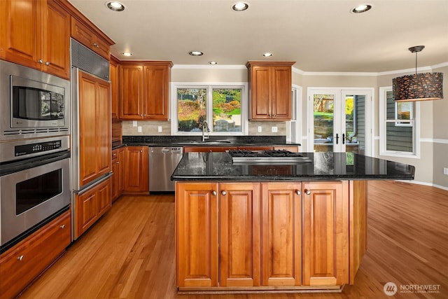 kitchen with stainless steel appliances, a sink, light wood-style flooring, and a healthy amount of sunlight