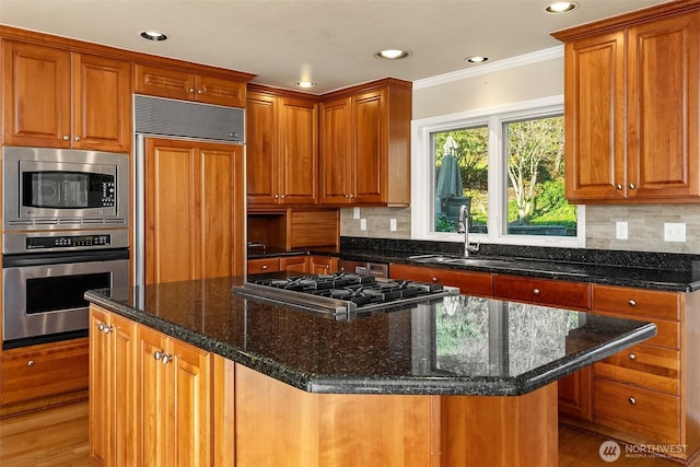 kitchen with tasteful backsplash, a center island, a sink, and built in appliances