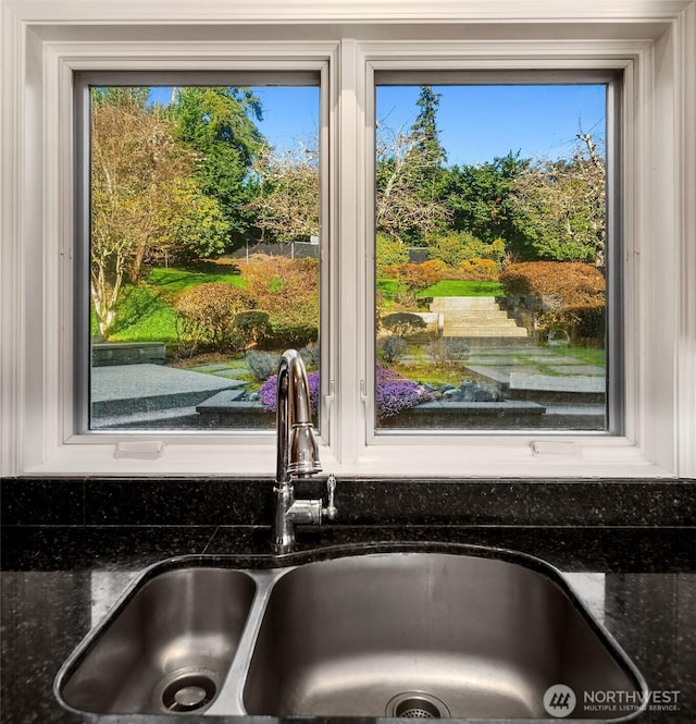 interior details featuring white cabinetry, dark stone counters, and a sink