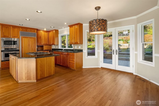 kitchen featuring tasteful backsplash, light wood-type flooring, crown molding, and built in appliances