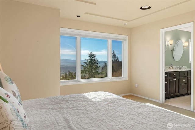 bedroom with recessed lighting, light colored carpet, a sink, baseboards, and ensuite bath