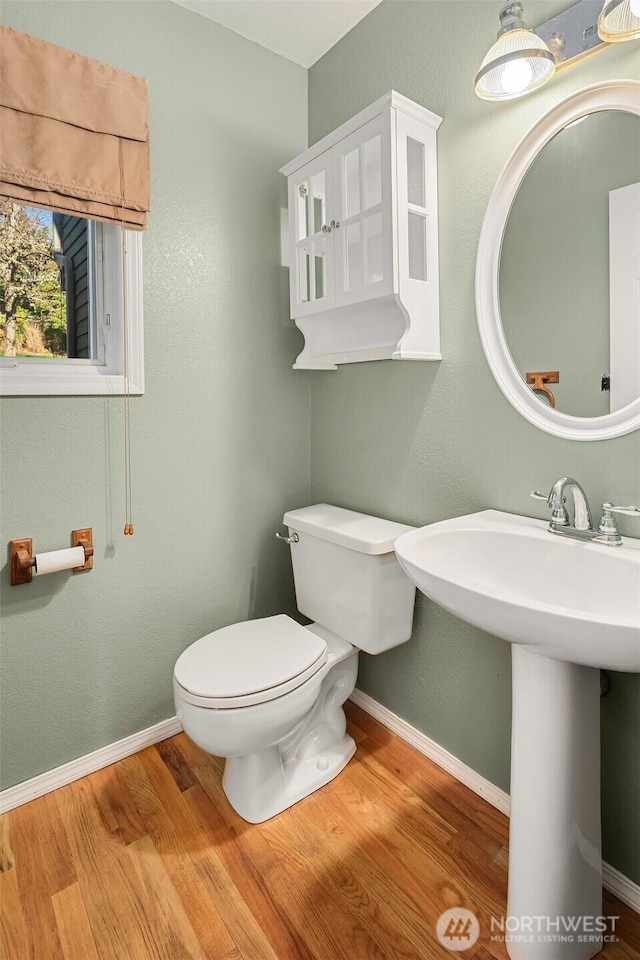 bathroom featuring toilet, baseboards, and wood finished floors