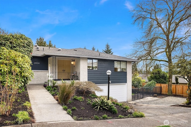 ranch-style house featuring brick siding, a shingled roof, driveway, and fence