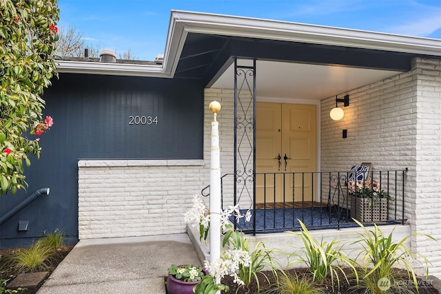 entrance to property featuring covered porch and brick siding