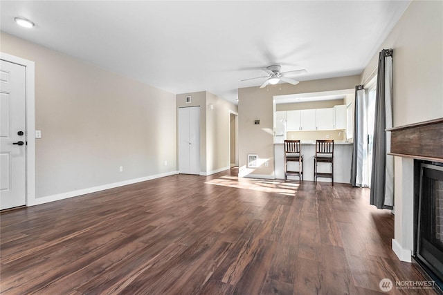 unfurnished living room with sink, dark hardwood / wood-style floors, and ceiling fan