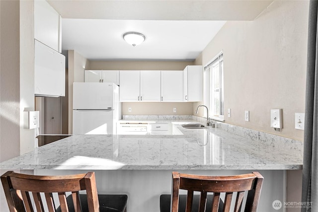 kitchen featuring sink, a breakfast bar, kitchen peninsula, and white refrigerator