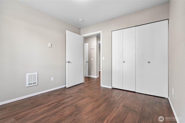 unfurnished bedroom featuring dark hardwood / wood-style flooring and a closet