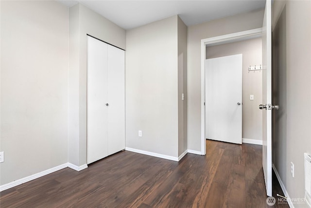 unfurnished bedroom featuring a closet and dark hardwood / wood-style floors